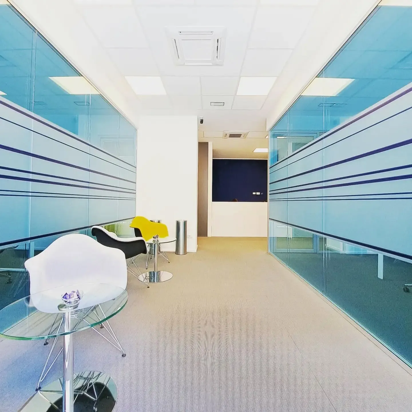 Corridoio di un ufficio con pellicole decorative azzurre e fasce orizzontali sulle pareti vetrate